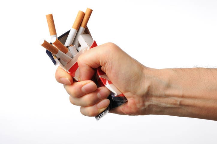 Immagine di una mano che stritola un pacchetto di sigarette