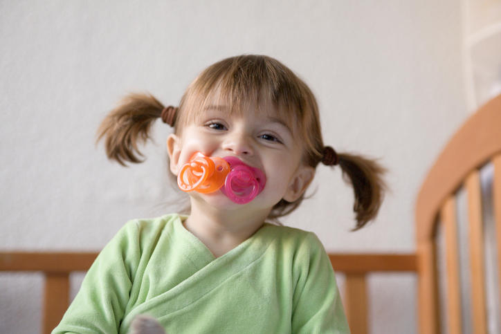 Bimba di circa 2 anni con due succhietti che ride