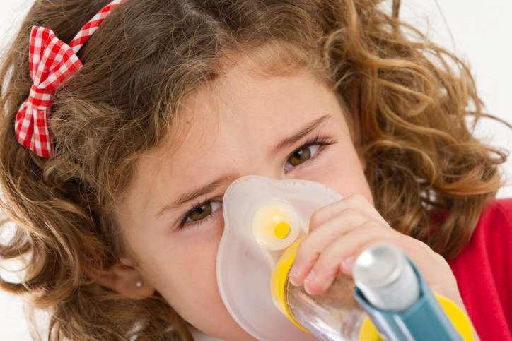 Fotografia ravvicinata di una bambina che assume un farmaco per la bronchiolite attraverso un distanziatore