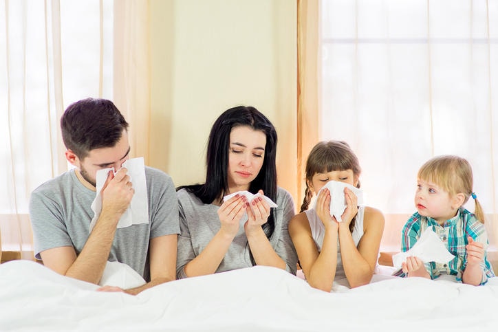 Fotografia di una famiglia a letto colpita da raffreddore