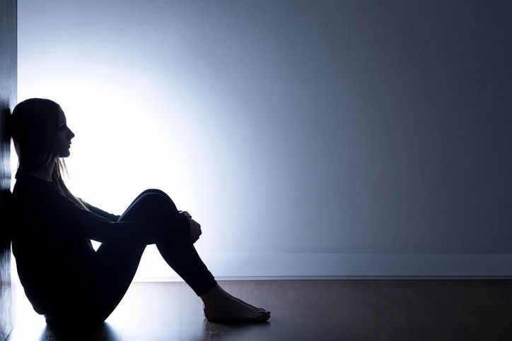 Immagine che ritrae una donna isolata e impotente nei confronti dell'ansia, appoggiata a un muro.