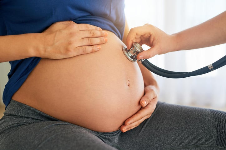Primo piano di uno stetoscopio appoggiato al pancione di una donna