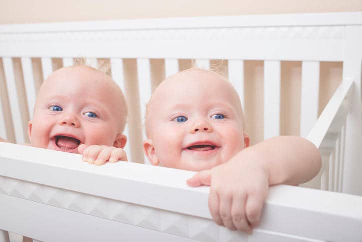 Foto di due bimbi gemelli affacciati al lettino