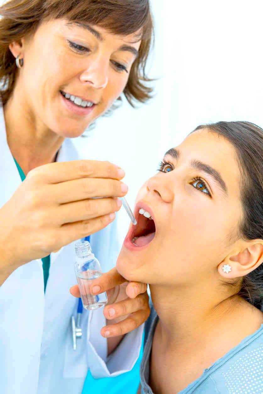 Immagine di una dottoressa che somministra il vaccino per via sublinguale a una giovane paziente.
