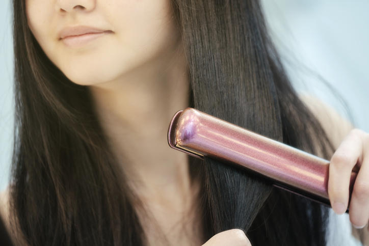 Donna che si stira i capelli con una piastra
