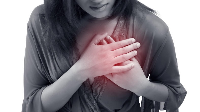 Fotografia di donna con le mani al petto, dove in genere si percepisce il dolore anginoso.