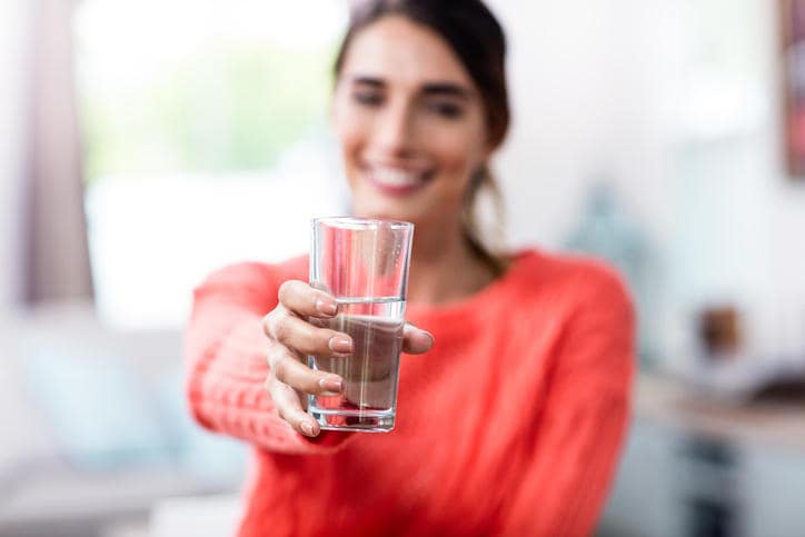 Donna che porge un bicchiere d'acqua, rimedio popolare per il singhiozzo