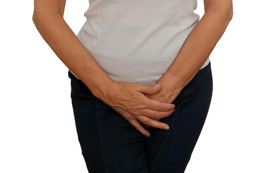 Primo piano del ventre di una donna, con le mani incrociate a livello pelvico