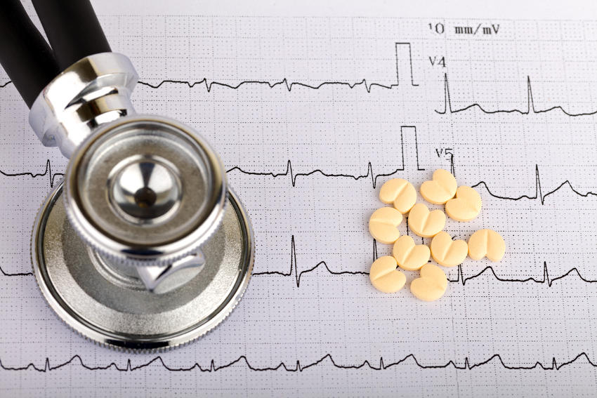 Tracciato di un elettrocardiogramma, con appoggiato uno stetoscopio e alcune pastiglie