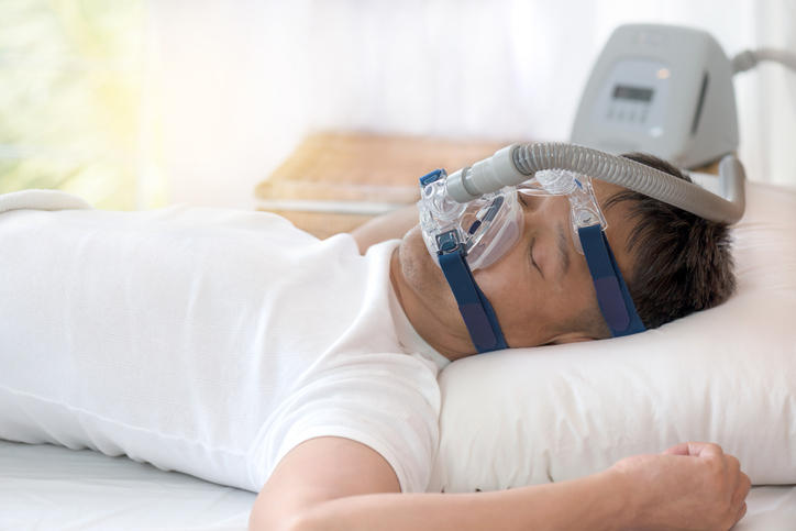 Fotografia di un uomo che dorme indossando un CPAP per la sindrome delle apnee notturne