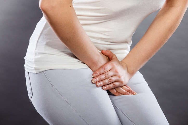 Primo piano di una donna che appoggia le mani all'altezza dei genitali a causa del fastidio avvertito