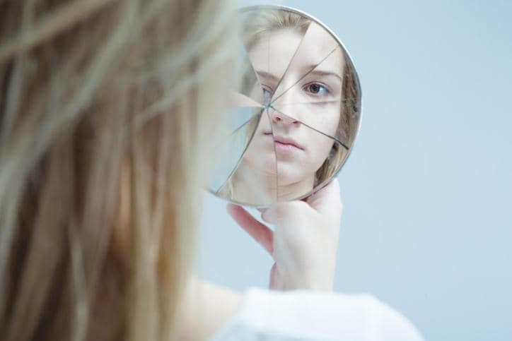 Ragazza di fronte a uno specchio rotto, che la riflette da varie angolature