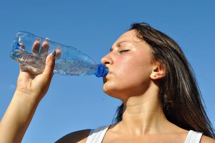 Fotografia di una donna che beve, per limitare il rischio di disidratazione legato all'esposizione al calore.