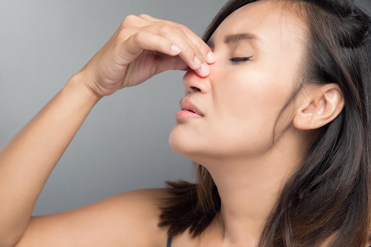 Donna che si tocca il naso a causa della congestione dovuta alla rinite vasomotoria