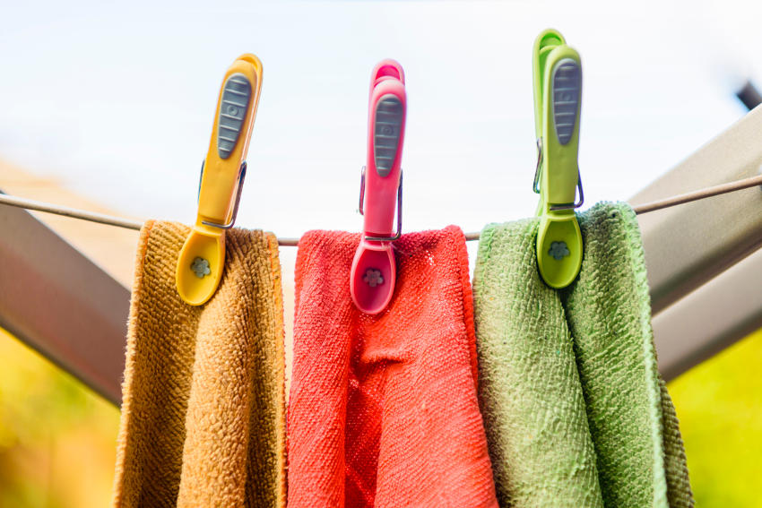 Tre asciugamani colorati, appesi con mollette dello stesso colore