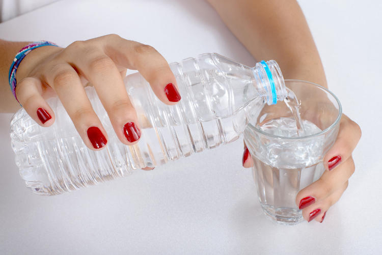 Donna che versa dell'acqua in un bicchiere