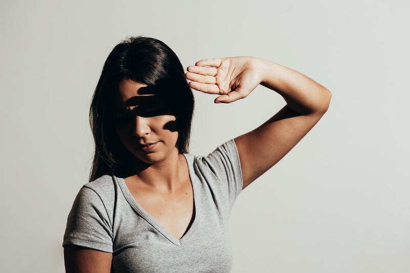 Donna che si ripara con una mano dalla luce solare