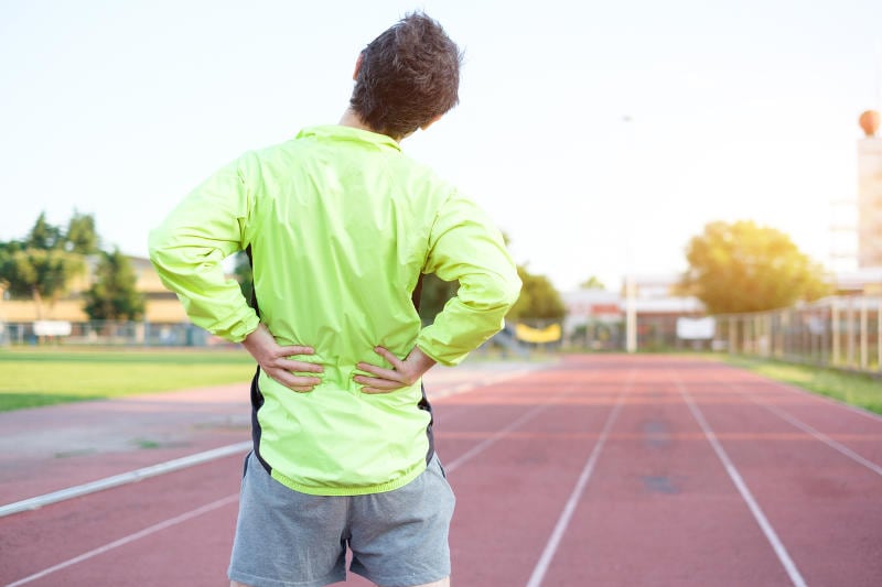 Atleta che si tocca la schiena a causa del dolore avvertito per una contrattura