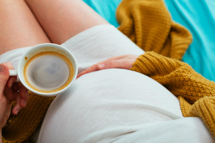 Donna in gravidanza che beve una tazza di caffè