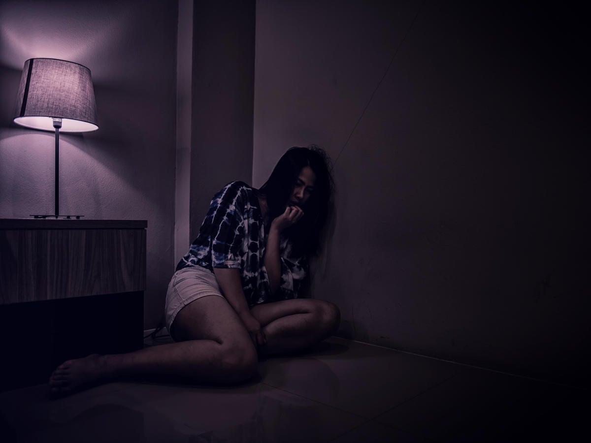 Donna sofferente in un angolo di una camera buia