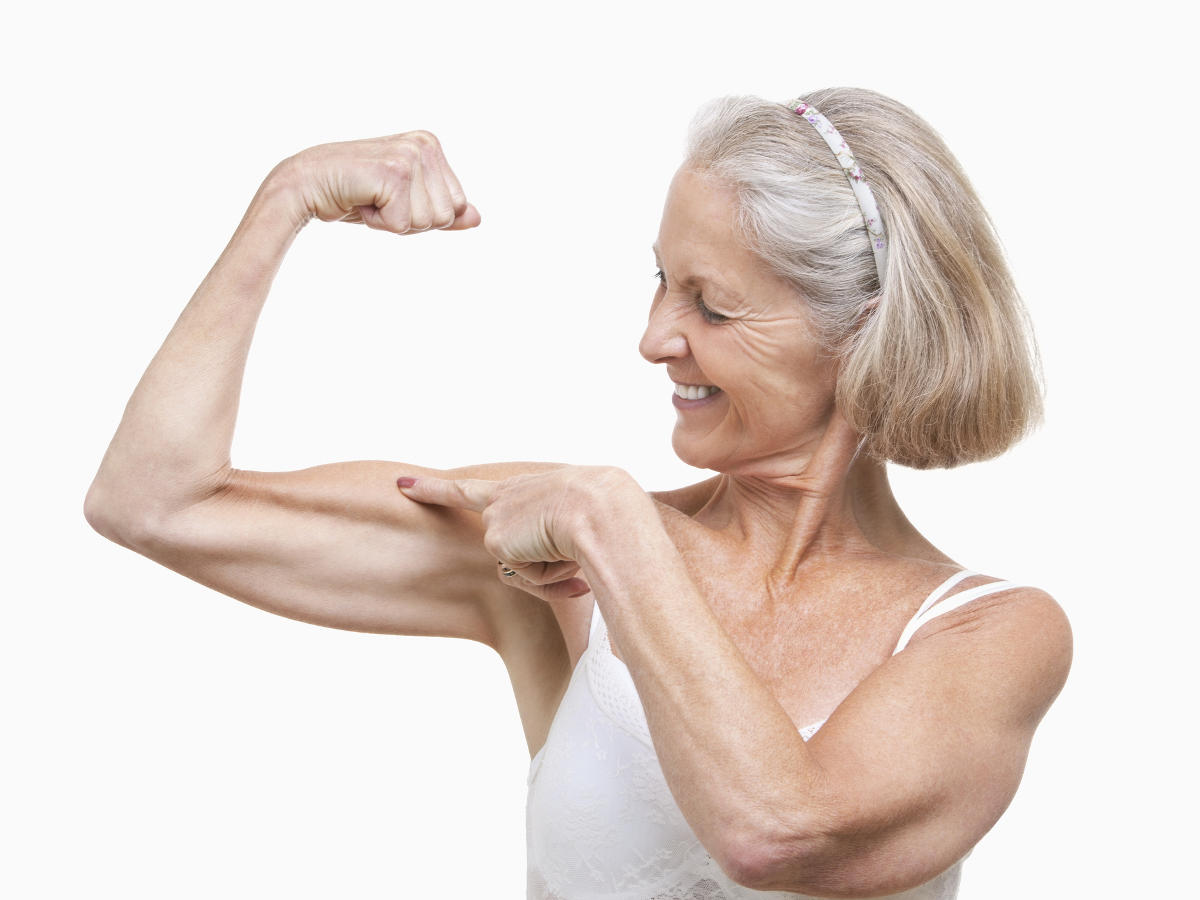 Donna con i capelli bianchi che indica il muscolo bicipite