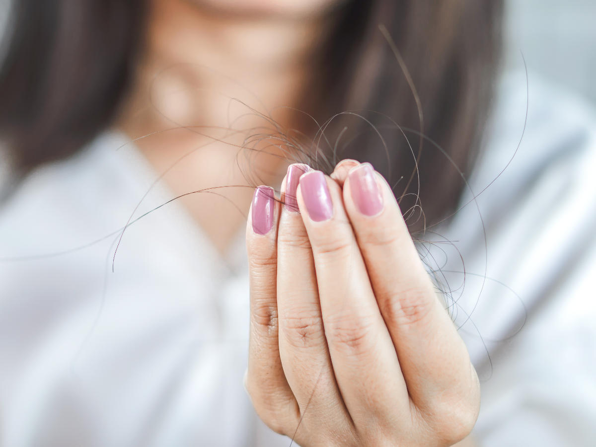 Mano di donna che tiene dei capelli strappati