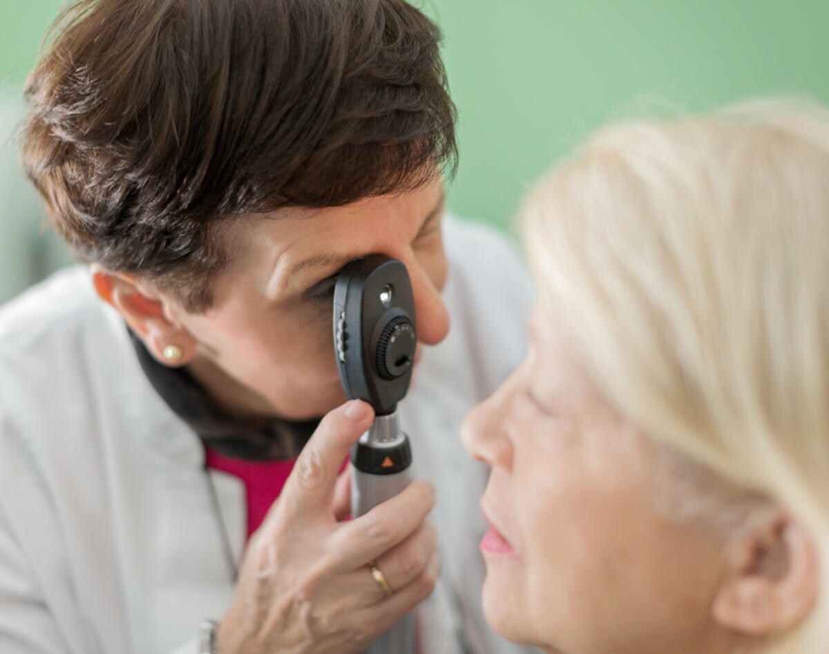 Oculista visita una donna con l'aiuto di un oftalmoscopio