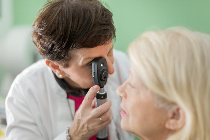 Oculista visita una donna con l'aiuto di un oftalmoscopio