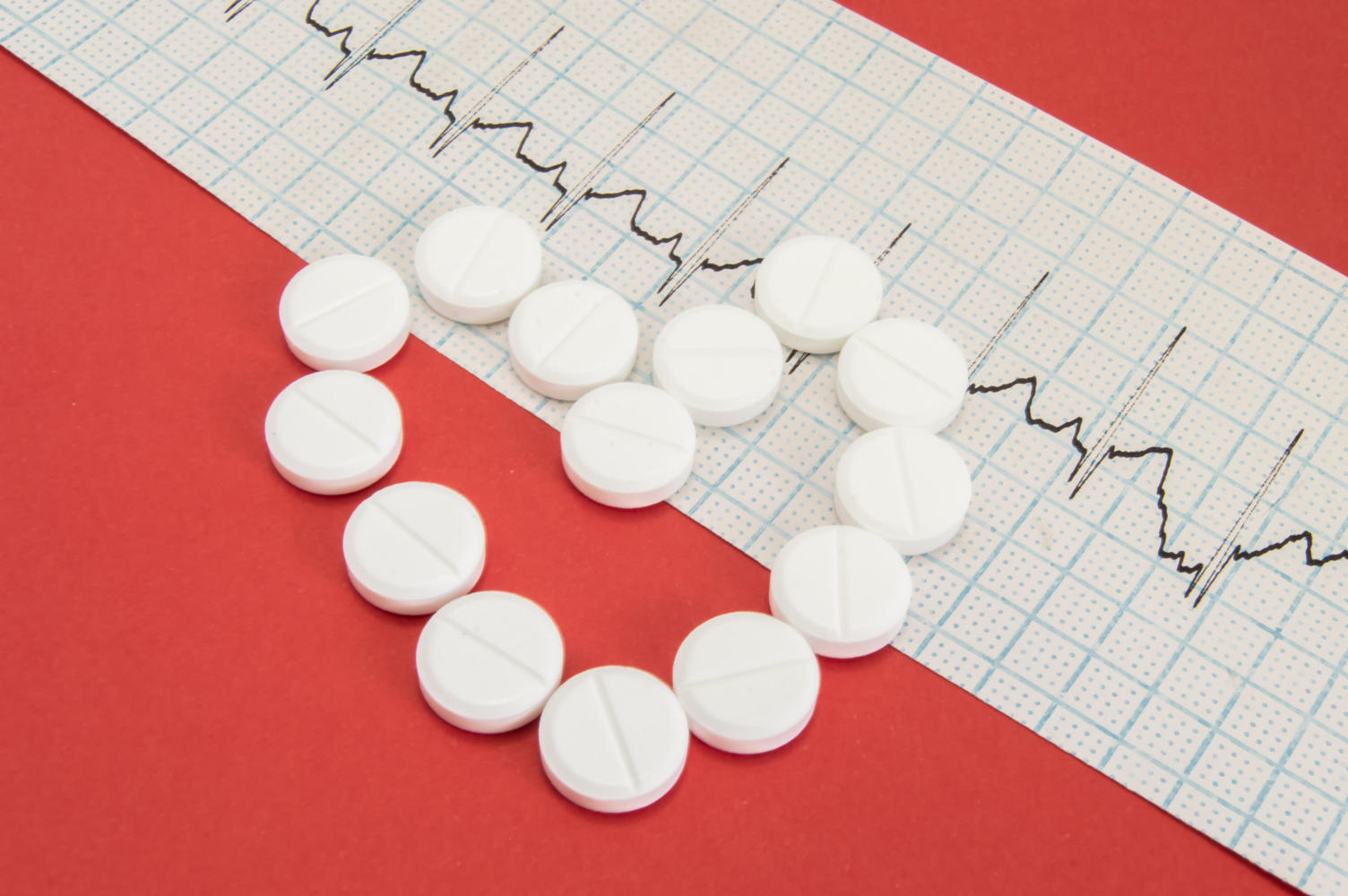Compresse disposte a forma di cuore, appoggiate sul referto di un elettrocardiogramma