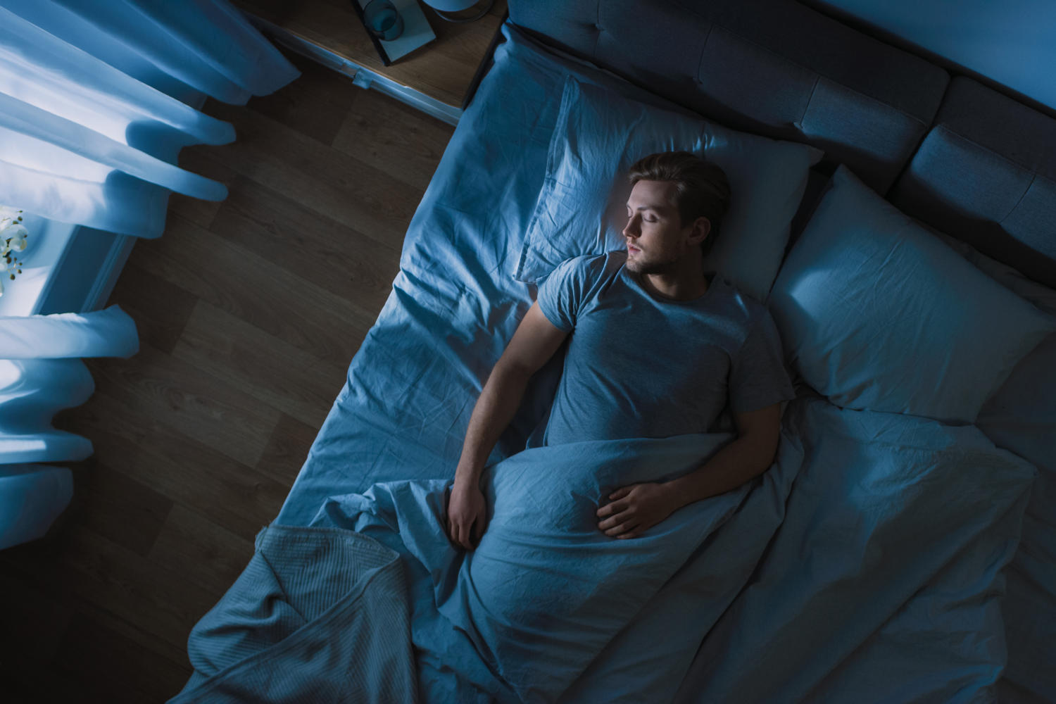 Uomo che dorme nel letto in una stanza buia
