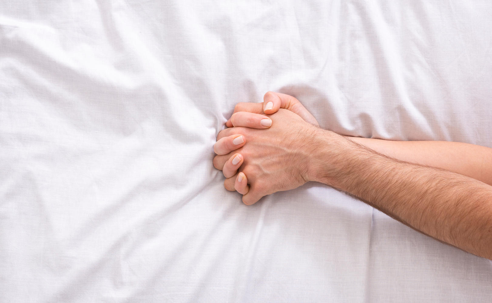 Mani intrecciate sopra un letto