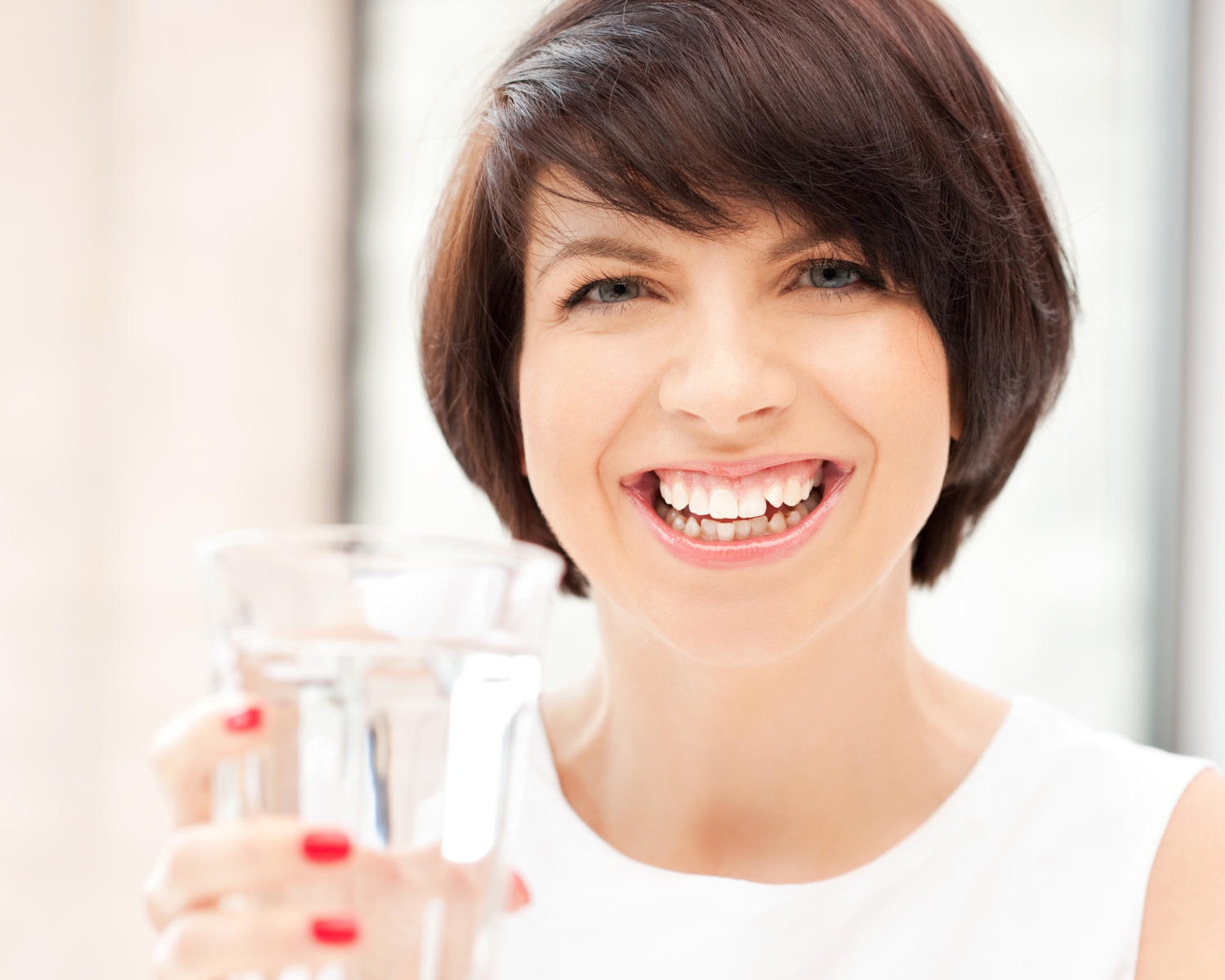 Donna che sorride e tiene in mano un bicchiere di acqua