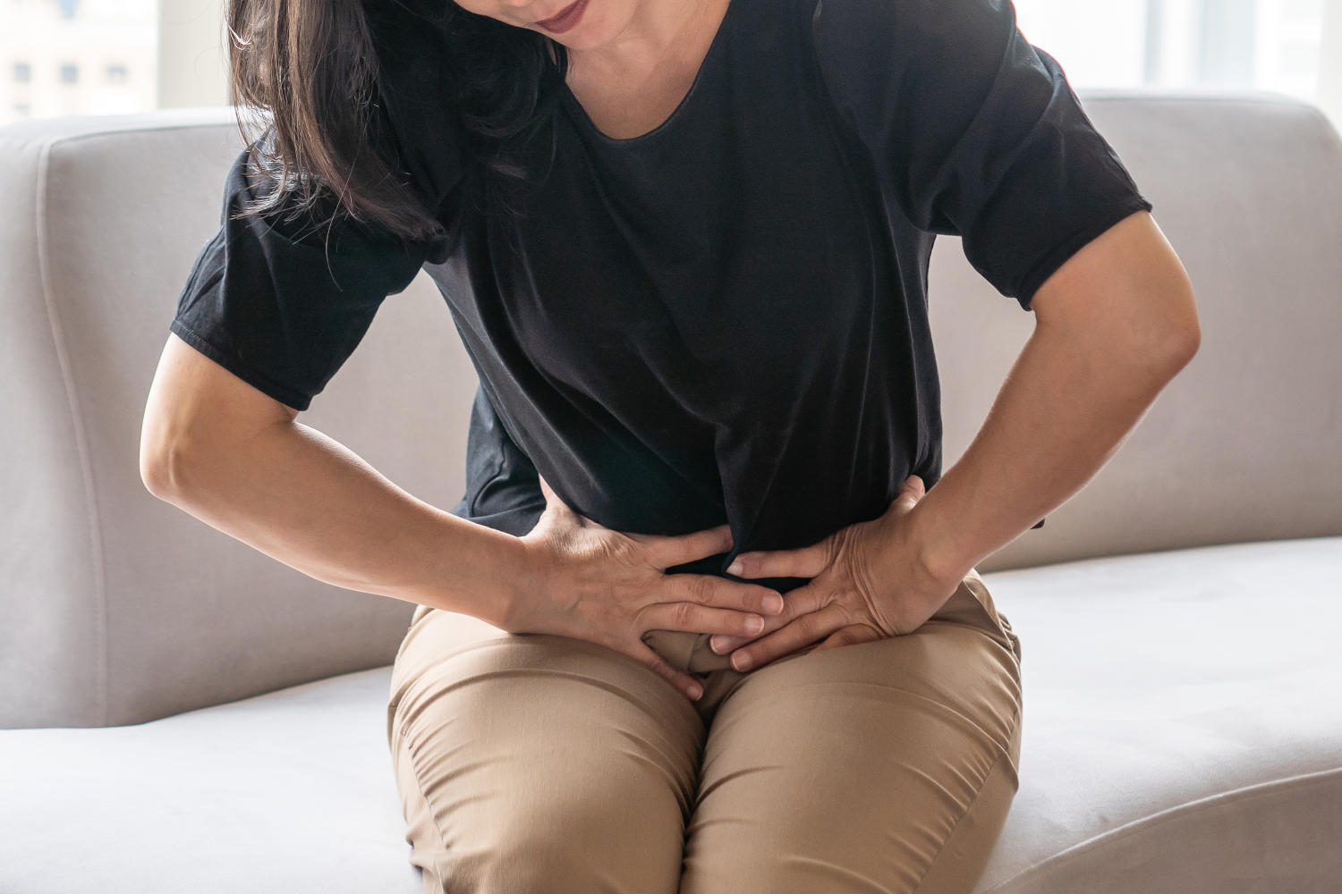 Donna con le mani appoggiate sull'area pelvica a causa di fastidio