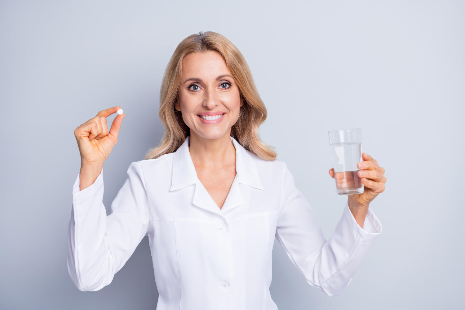 Donna che tiene in mano una compressa e un bicchiere d'acqua