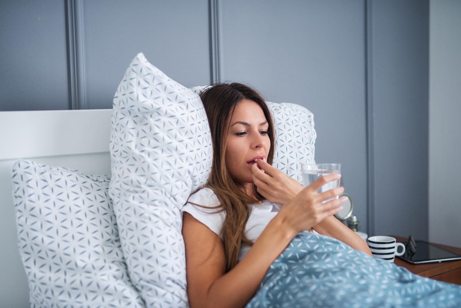 Donna nel letto che sta per assumere una compressa