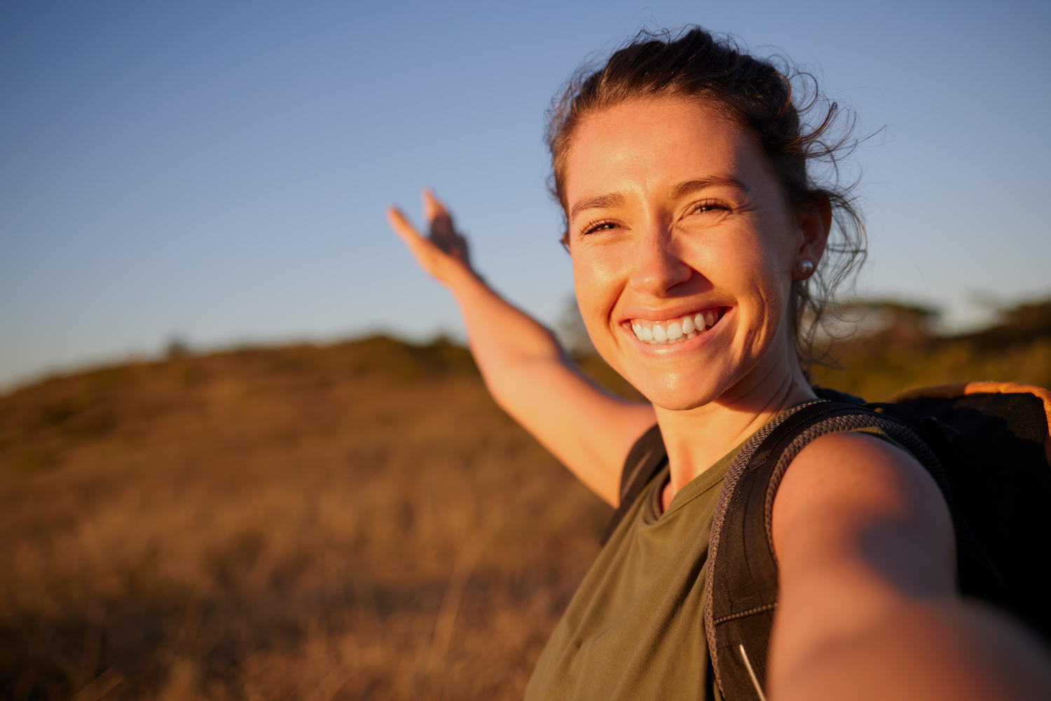 Ragazza che guarda in camera e indica il paesaggio naturale dietro