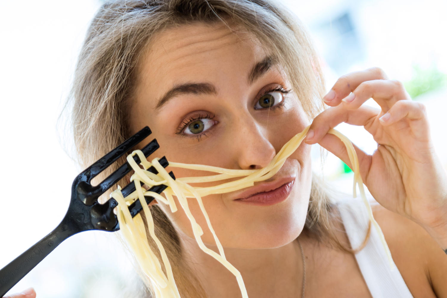 Donna che usa spaghetti come baffi finti