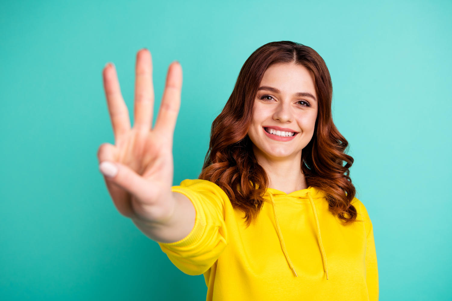 Ragazza che guarda in camera e indica 3 con la mano