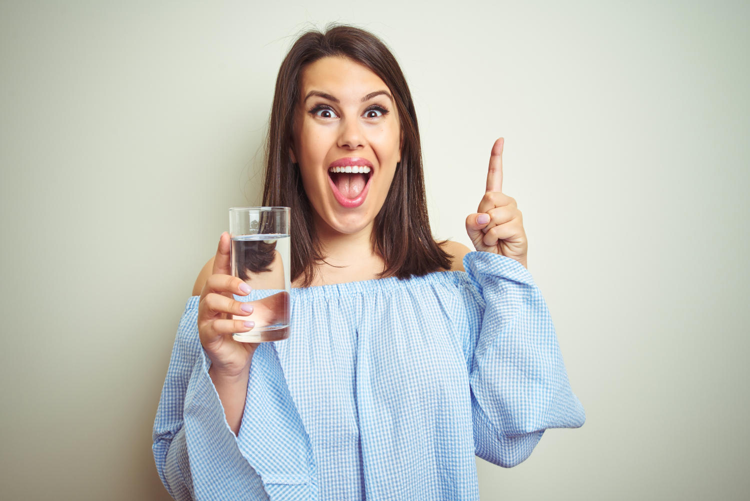 Ragazza con in mano un bicchiere d'acqua e la faccia soddisfatta