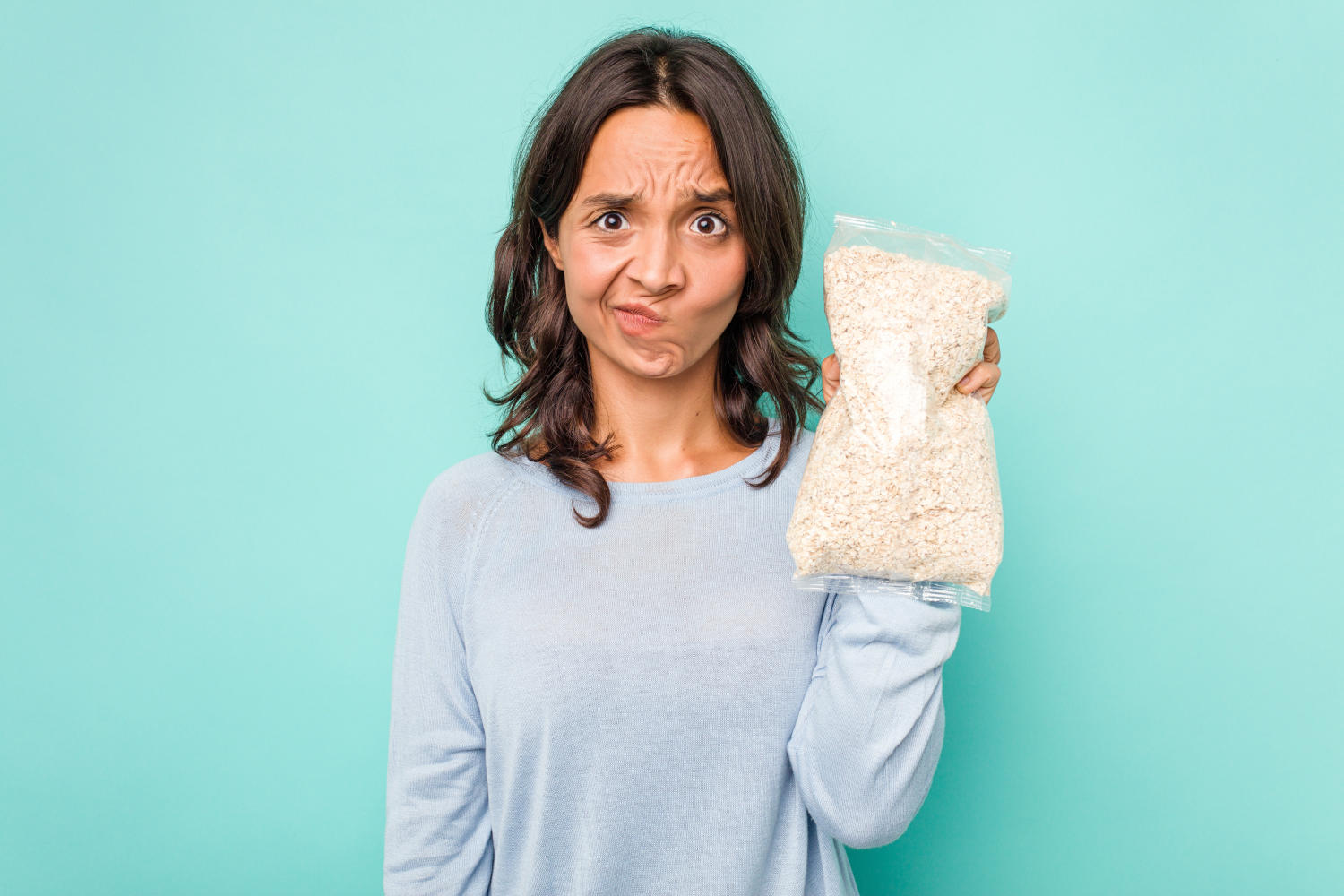 Ragazza con espressione dubbiosa e in mano un pacco di fiocchi di avena