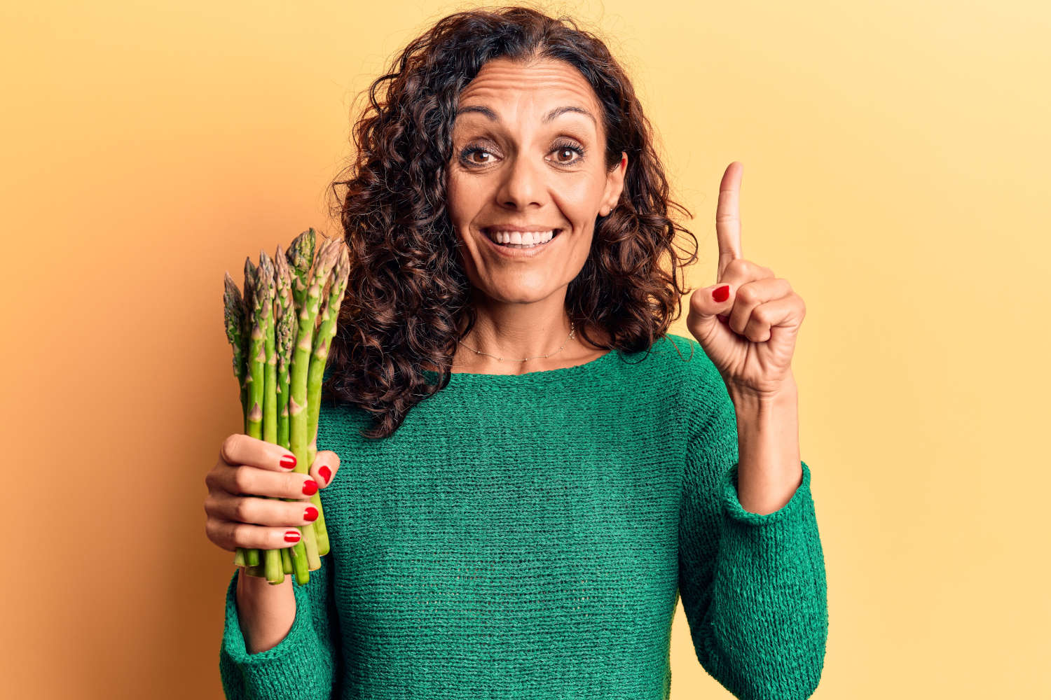 Donna che tiene in mano un mazzetto di asparagi verdi