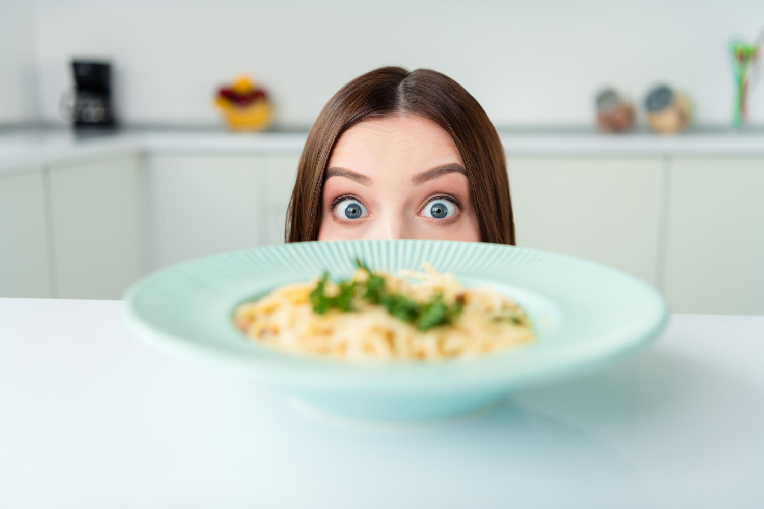 Ragazza che guarda con occhi buffi un piatto di pasta