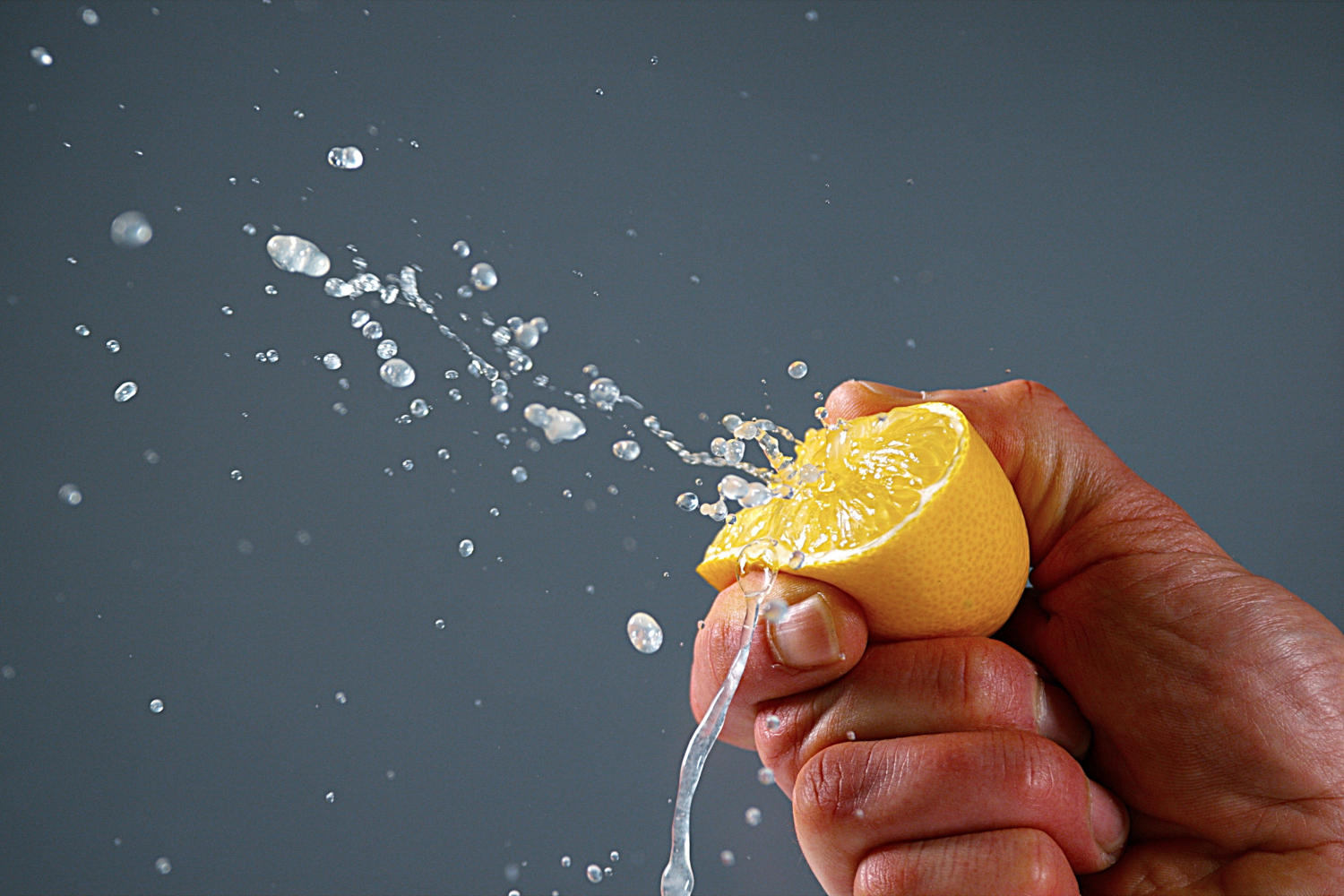 Una mano strizza un mezzo limone