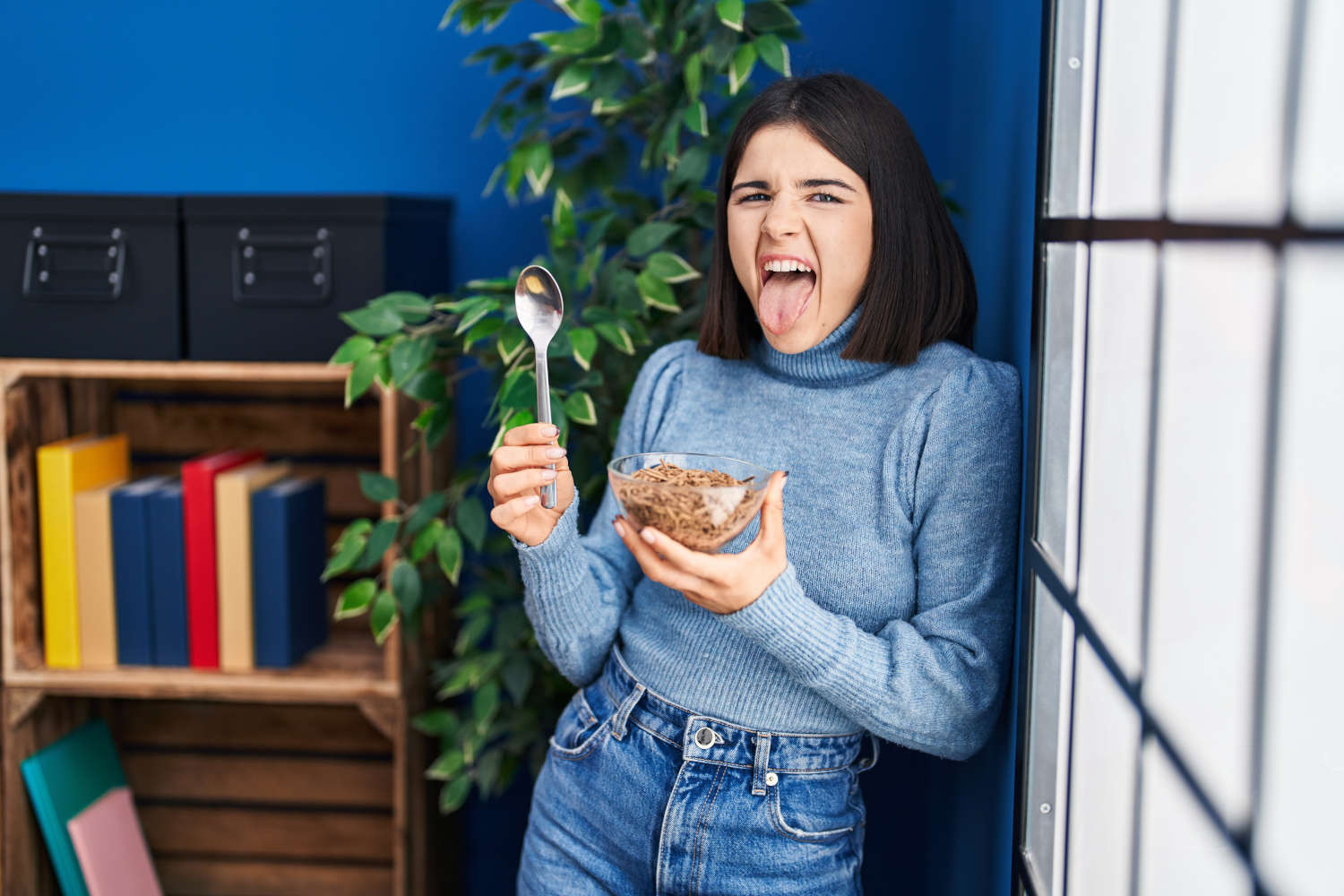 Ragazza che fa una linguaccia mentre mangia una tazza di cereali