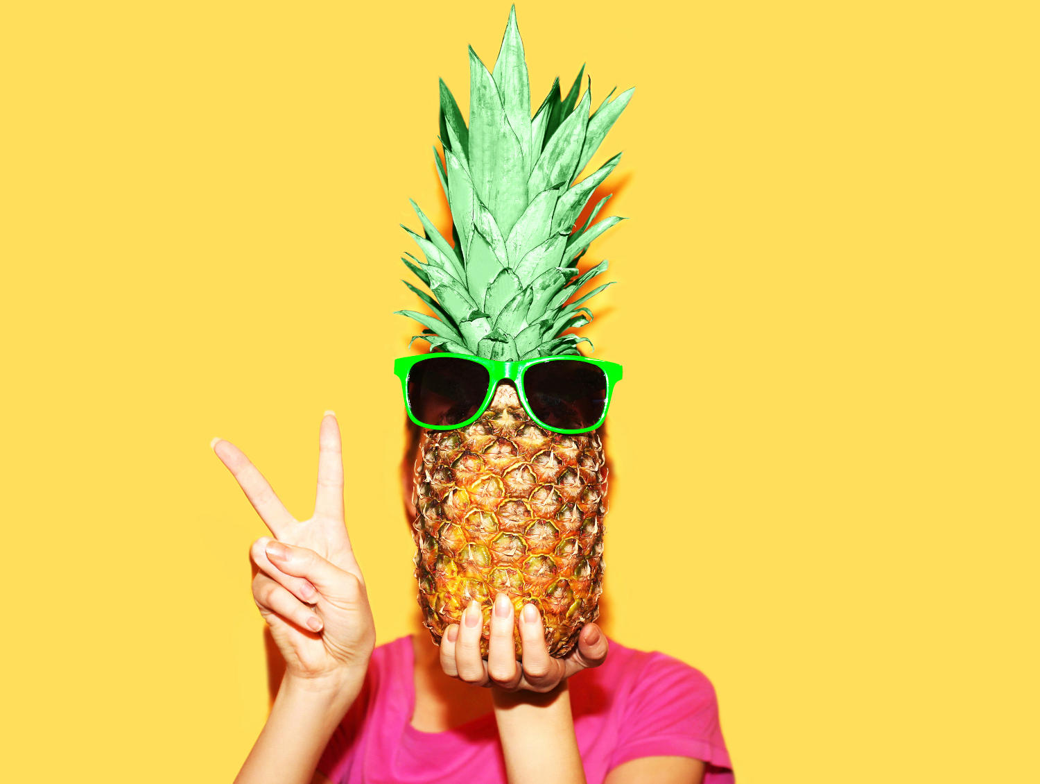 Ragazza con un'ananas di fronte al viso (con degli occhiali da sole)