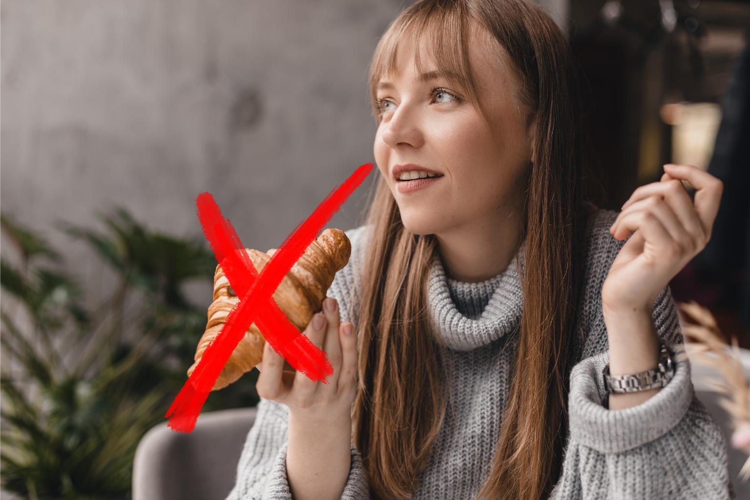 Ragazza che mangia un croissant per colazione (c'è una croce sul croissant)