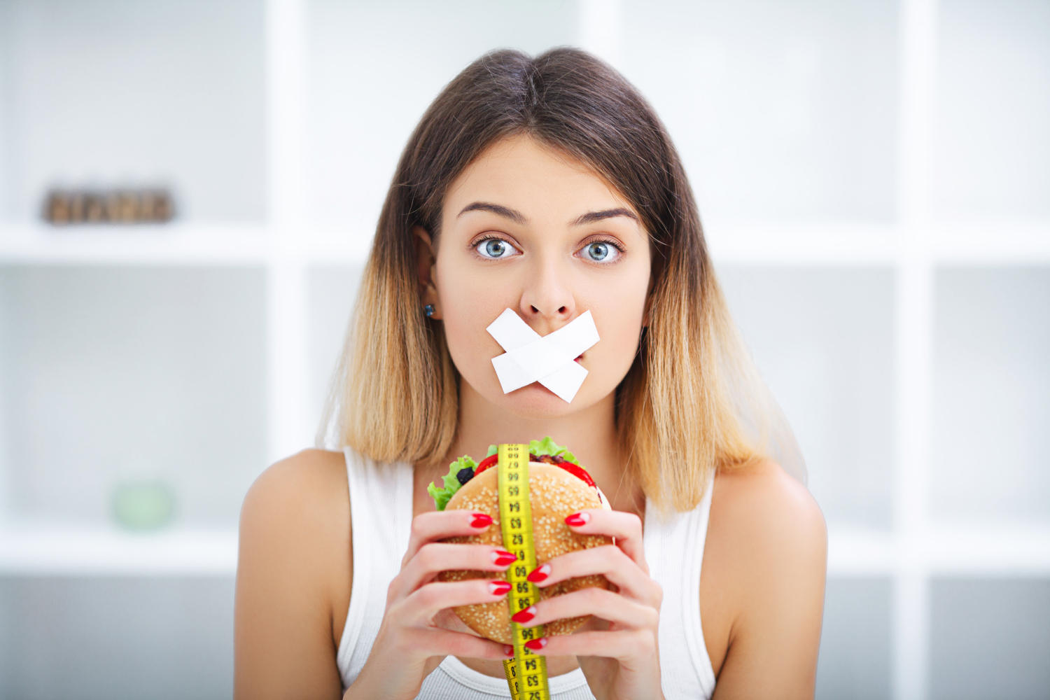 Ragazza con un cerotto sulla bocca e un hamburger in mano