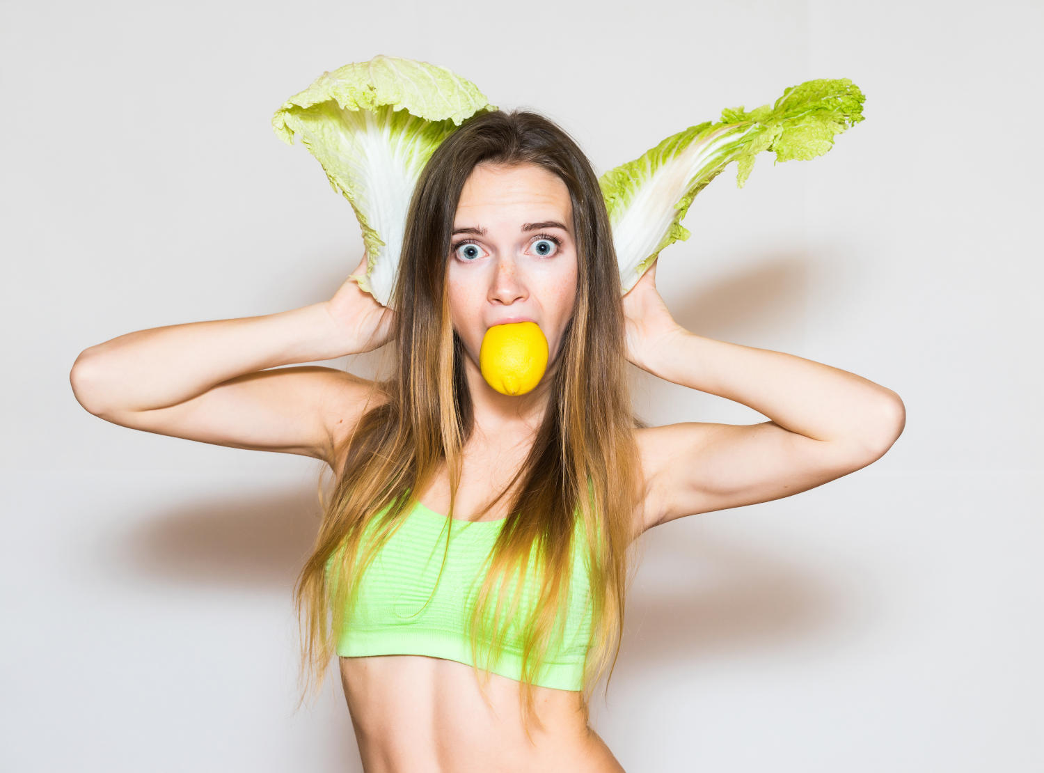 Ragazza con sguardo buffo e due foglie d'insalata al posto delle orecchie