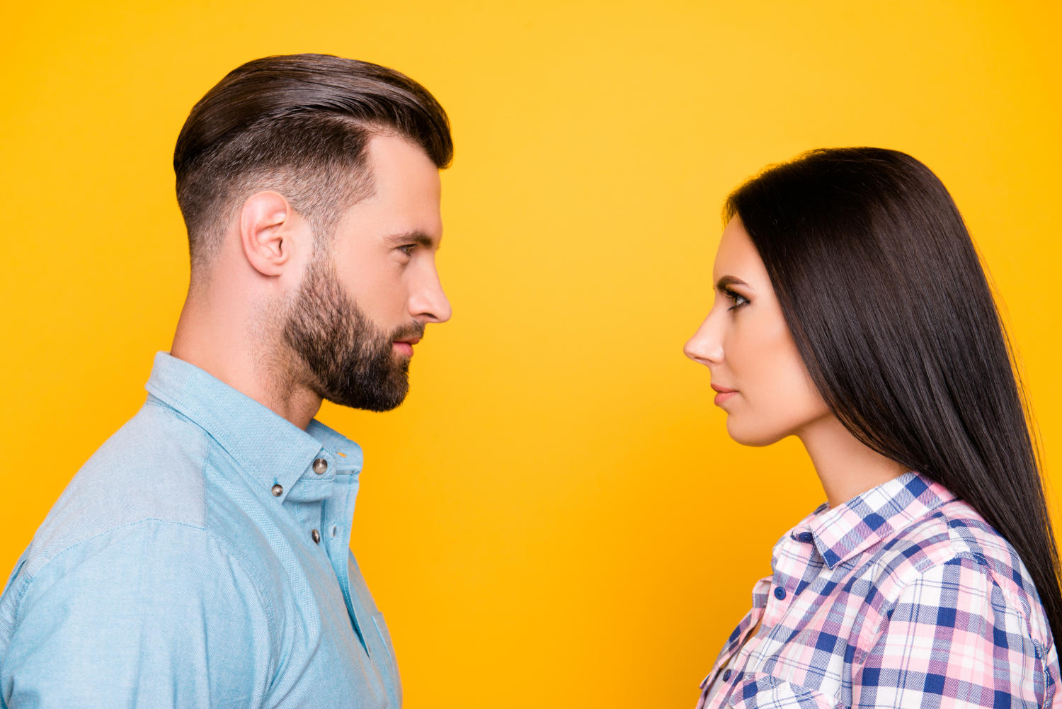 Uomo e donna che si guardano negli occhi su sfondo giallo