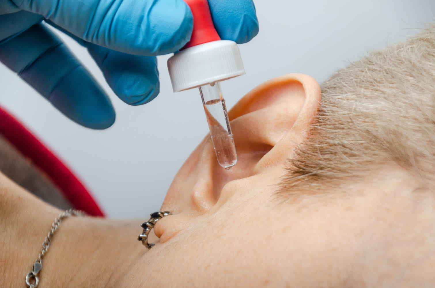Medico fa cadere alcune gocce da un contagocce nell'orecchio di una paziente